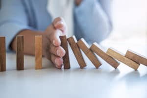Image of hand stopping falling collapse wooden block dominoes effect from continuous toppled block