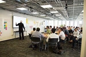 Jeff Sutherland pointing at a whiteboard while a class of students looks on.