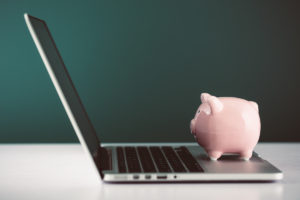 Piggy bank sitting on an open laptop