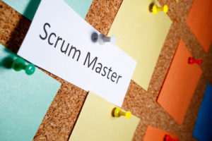 Scrum master is written on a piece of paper which on a bun is attached to a board