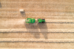 Aerial view of John Deere equipment baling a row of hay in a field